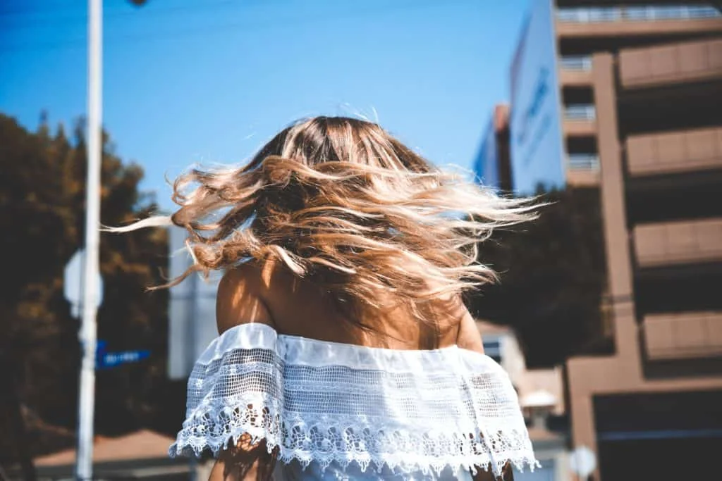How to Get Glowing Summer Skin in Raleigh - woman flipping hair in the summer
